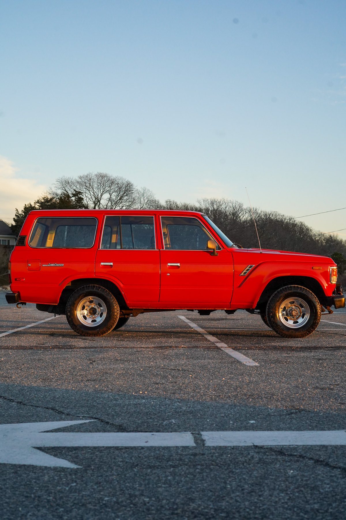 Red Toyota Land Cruiser parked at a Cape Cod beach lot at sunset