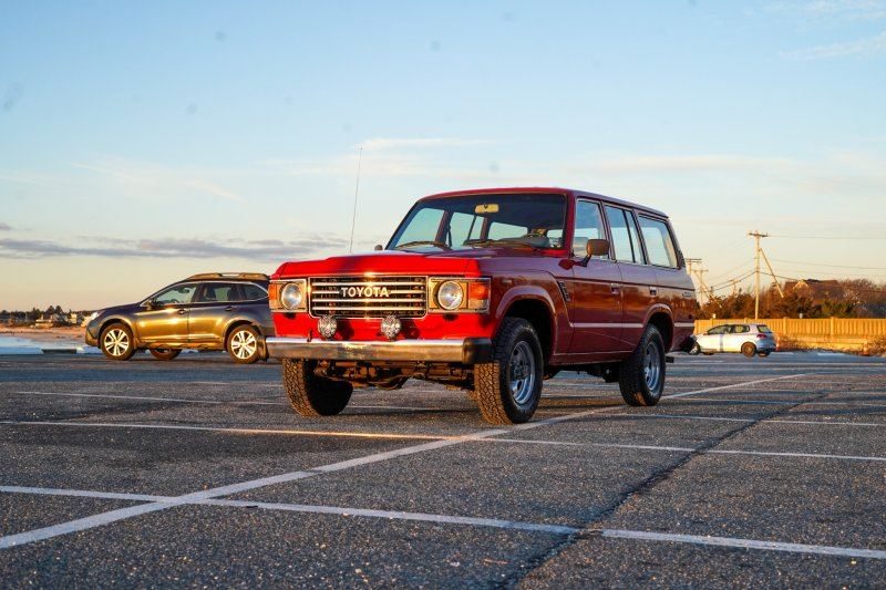 Red 1987 Toyota Land Cruiser FJ60 at sunrise beside the water